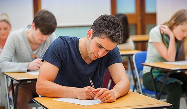 A student doing an exam sitting at a desk in a classroom