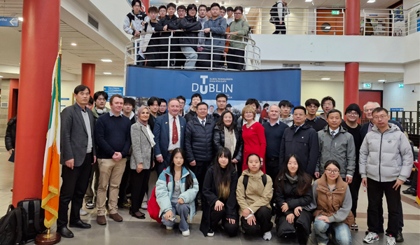 A group of students and staff pose for a photo with a delegation from Nanjing Tech University