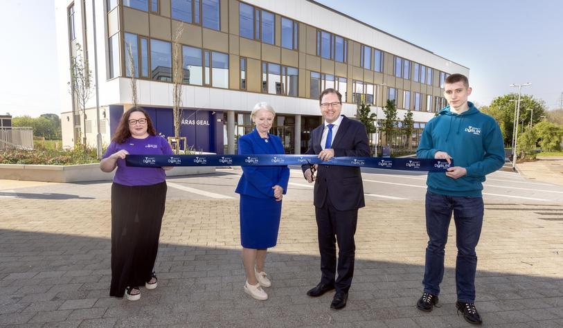 A group of people holding a ribbon in front of a building